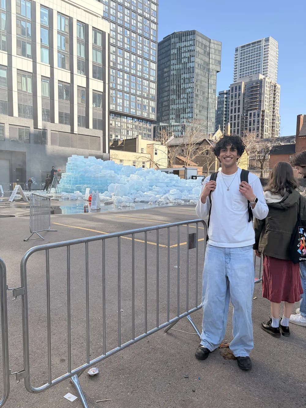 Shaan downtown in front of an ice sculpture, towers behind him